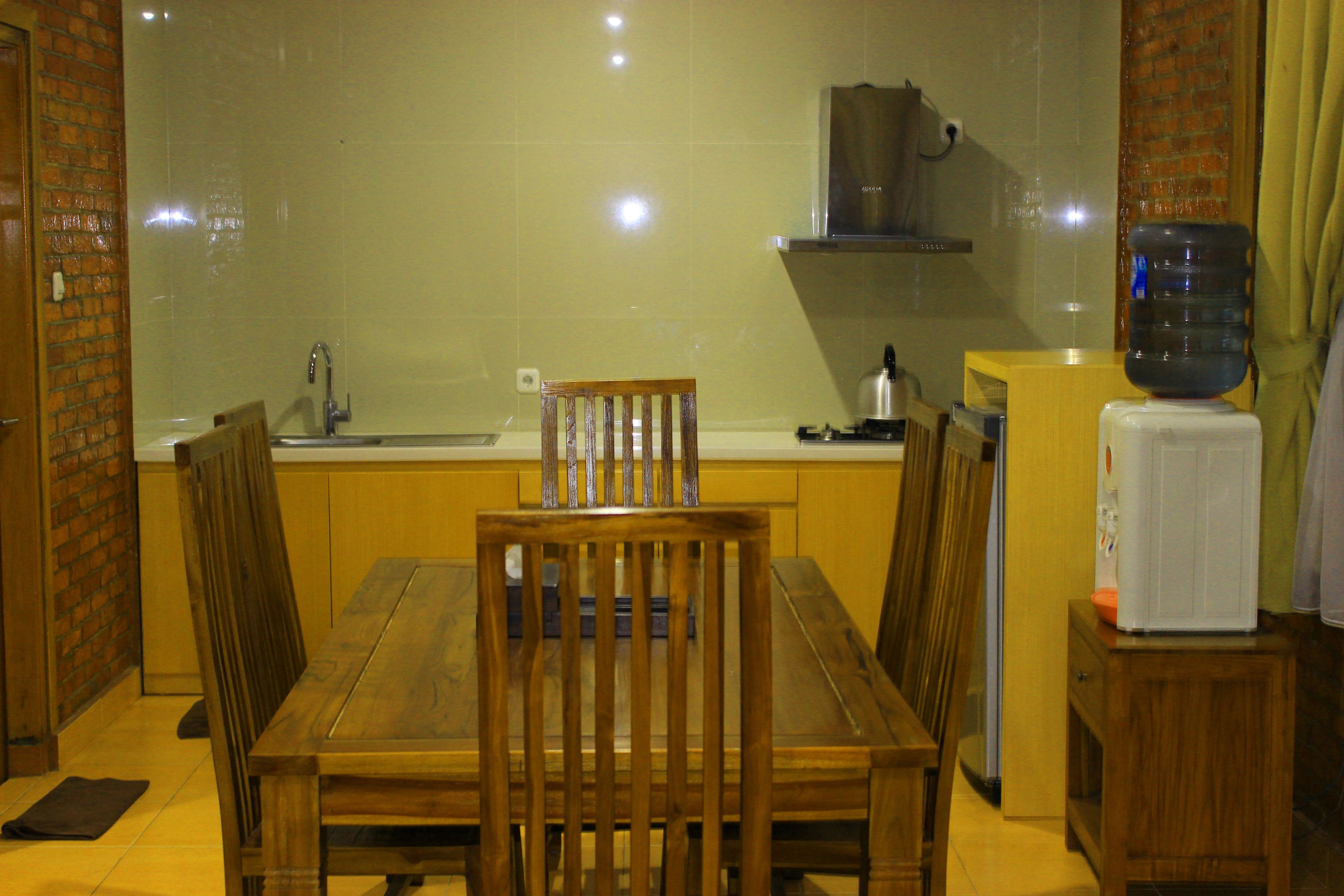 Una cocina compacta con una mesa de comedor de madera, un lavamanos y un dispensador de agua.