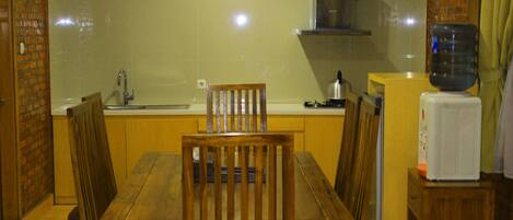 Una cocina compacta con una mesa de comedor de madera, un lavamanos y un dispensador de agua.