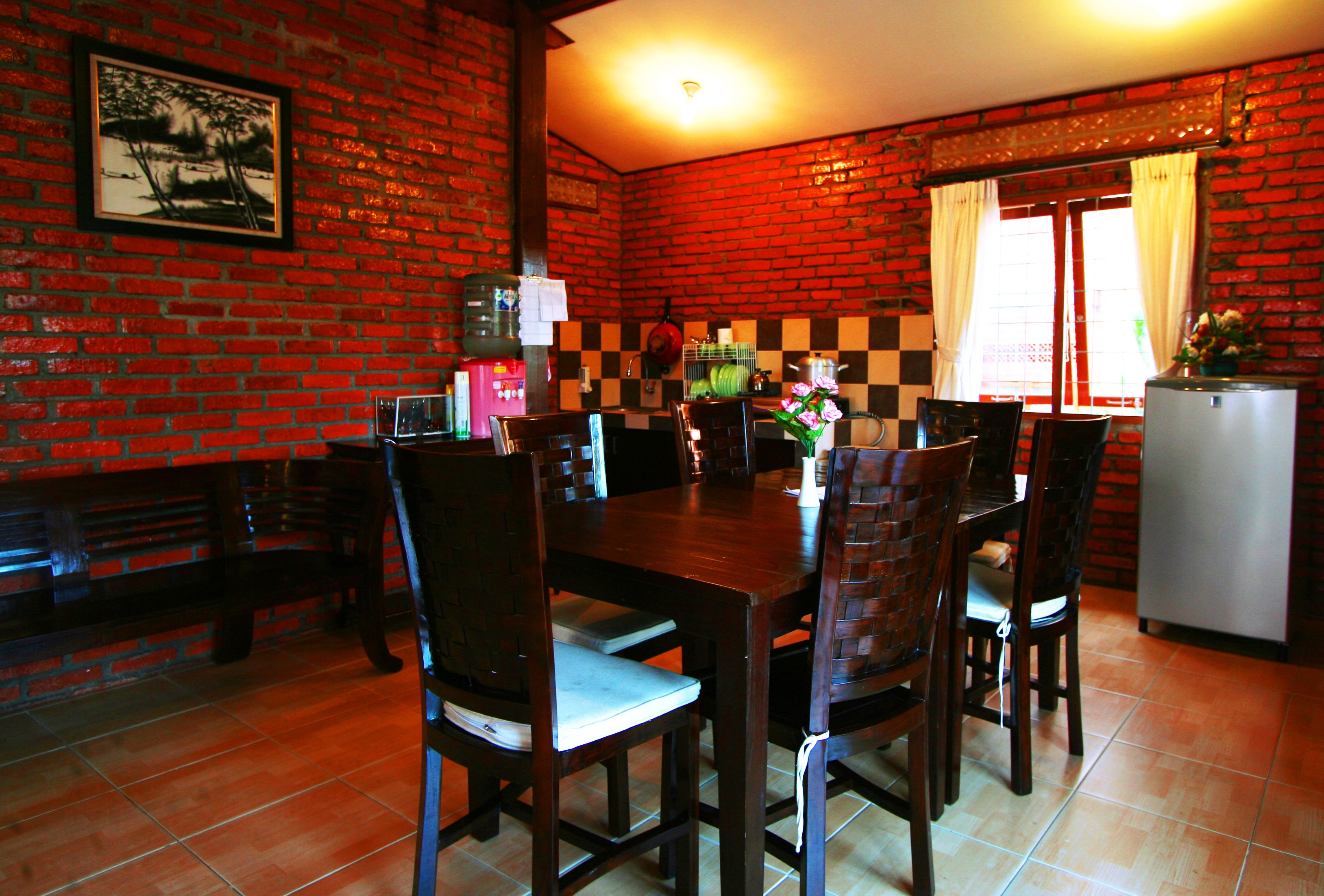 Un comedor con pared de ladrillo, salpicadero a cuadros y piso de baldosas.