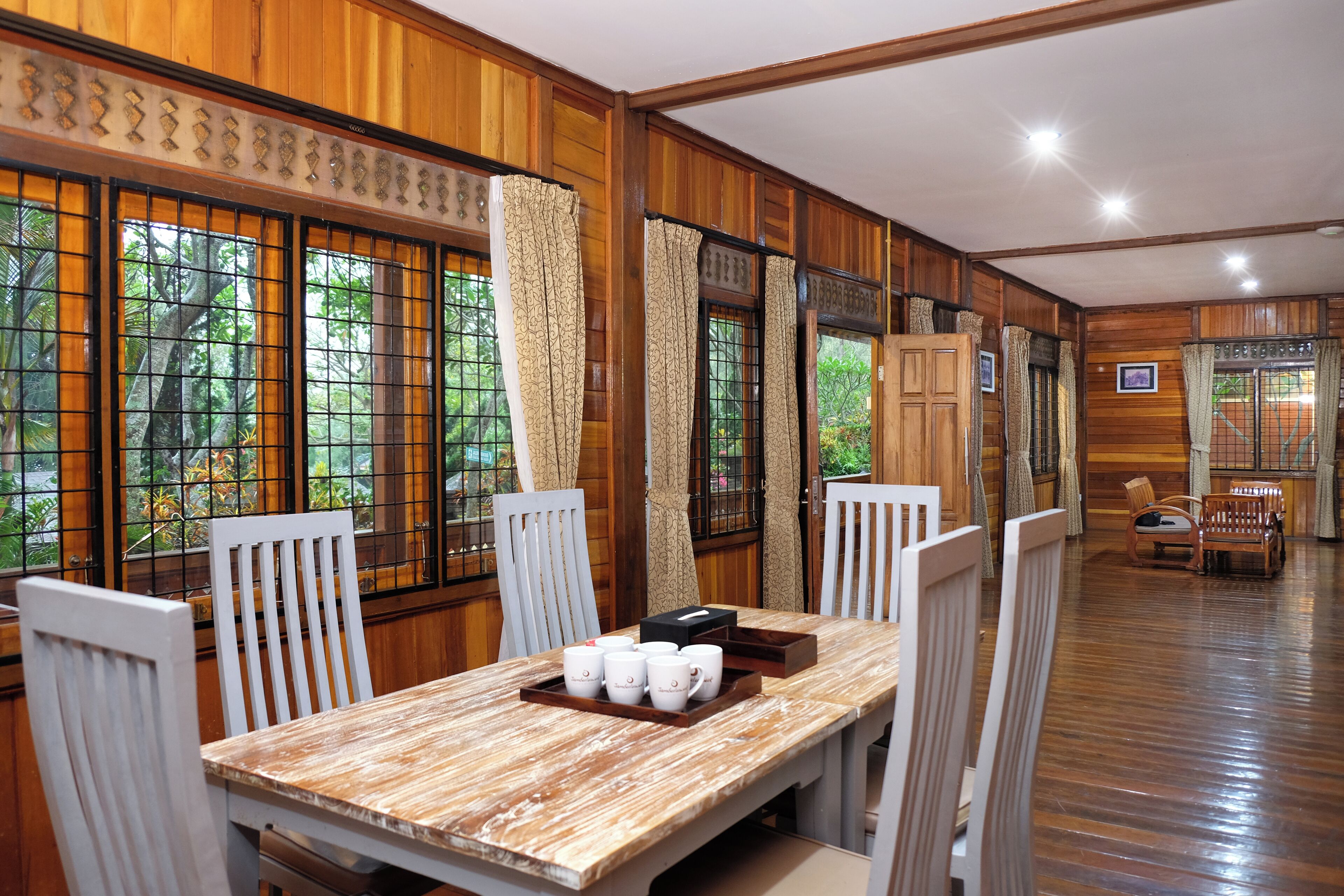A wooden-paneled room with a dining table set for six, surrounded by white chairs.