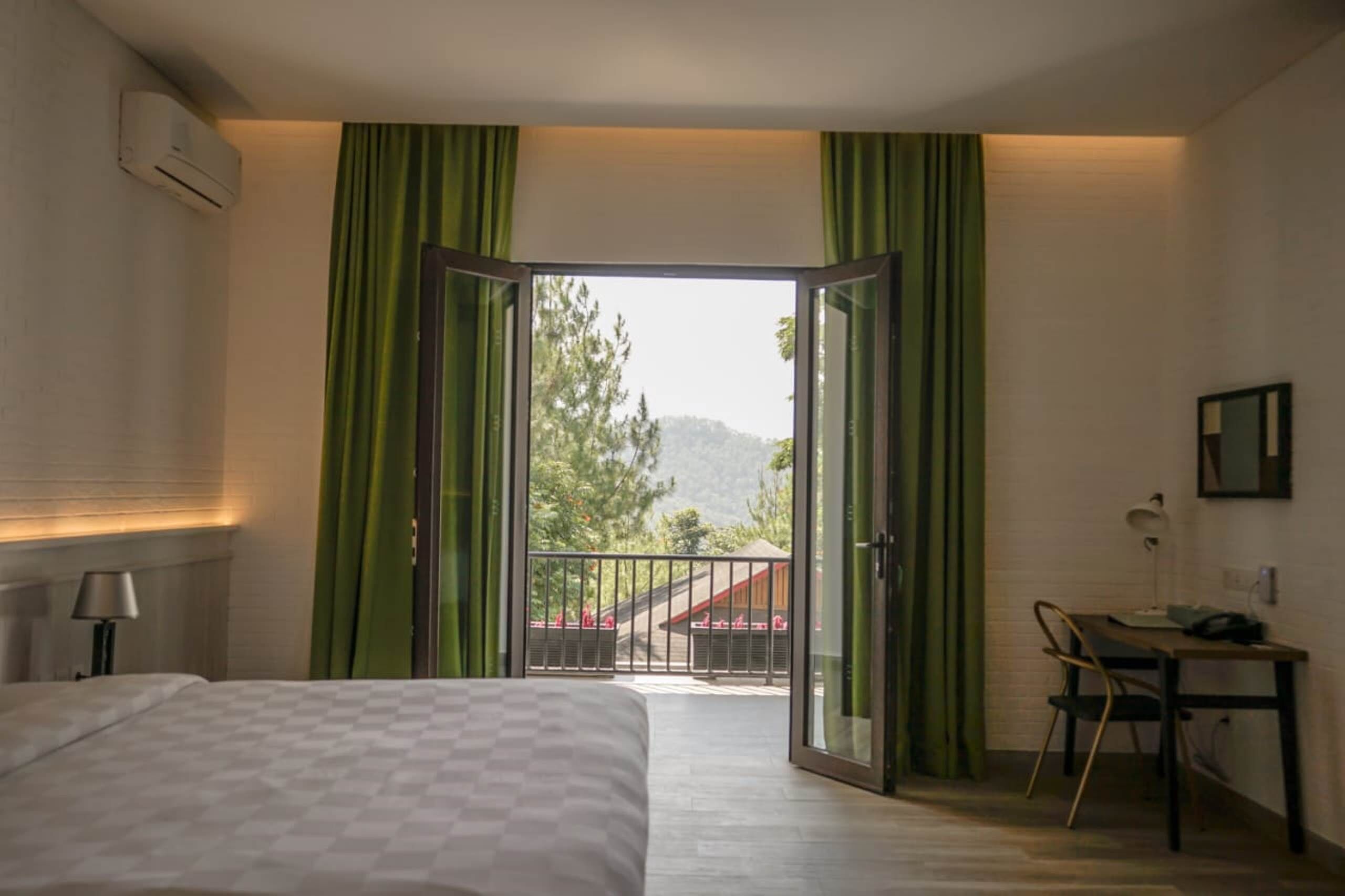 Una habitación de hotel con cama, escritorio y vistas a un balcón con barandilla.