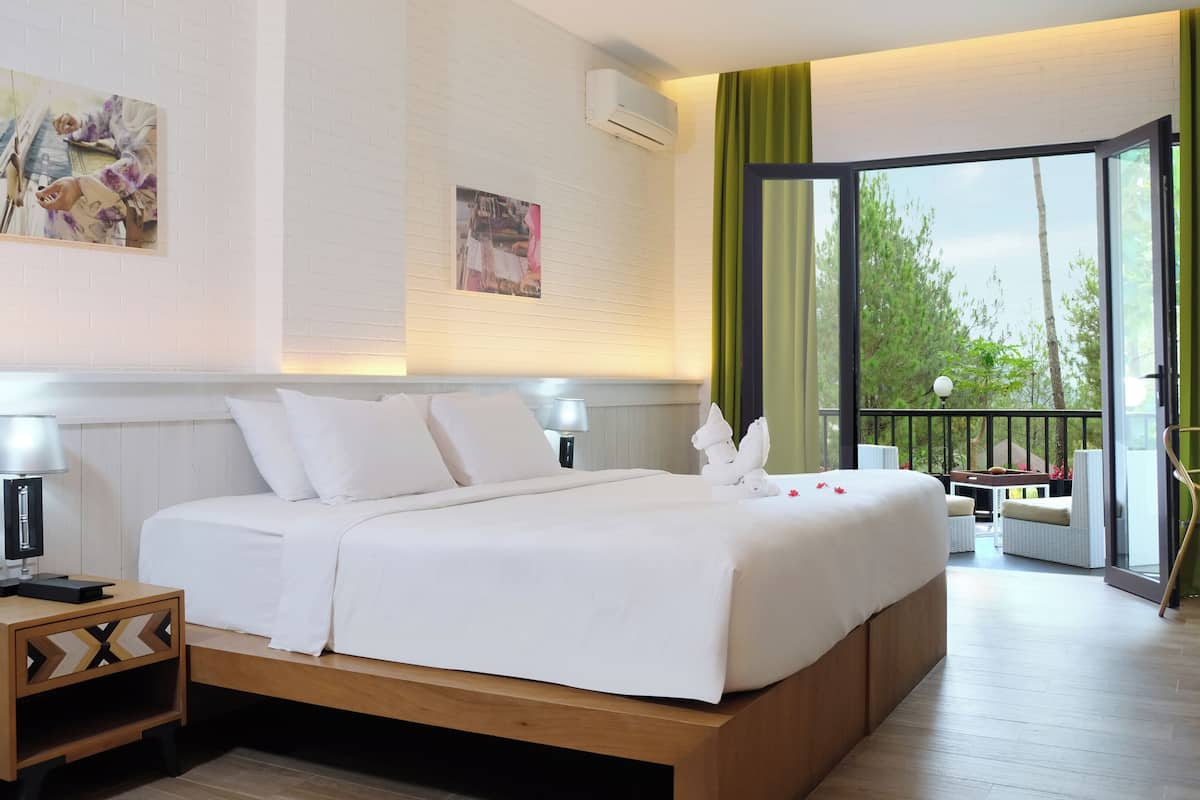 Ein Hotelzimmer mit Bett, Nachttischen, einem Schreibtisch und einem Balkon mit Blick.