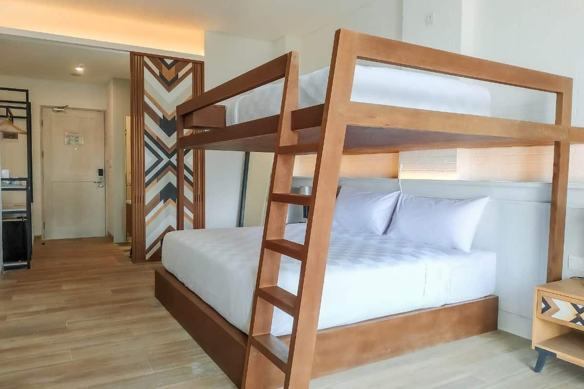 Ein Etagenbett mit Holzrahmen und weißer Bettwäsche in einem Hotelzimmer.
