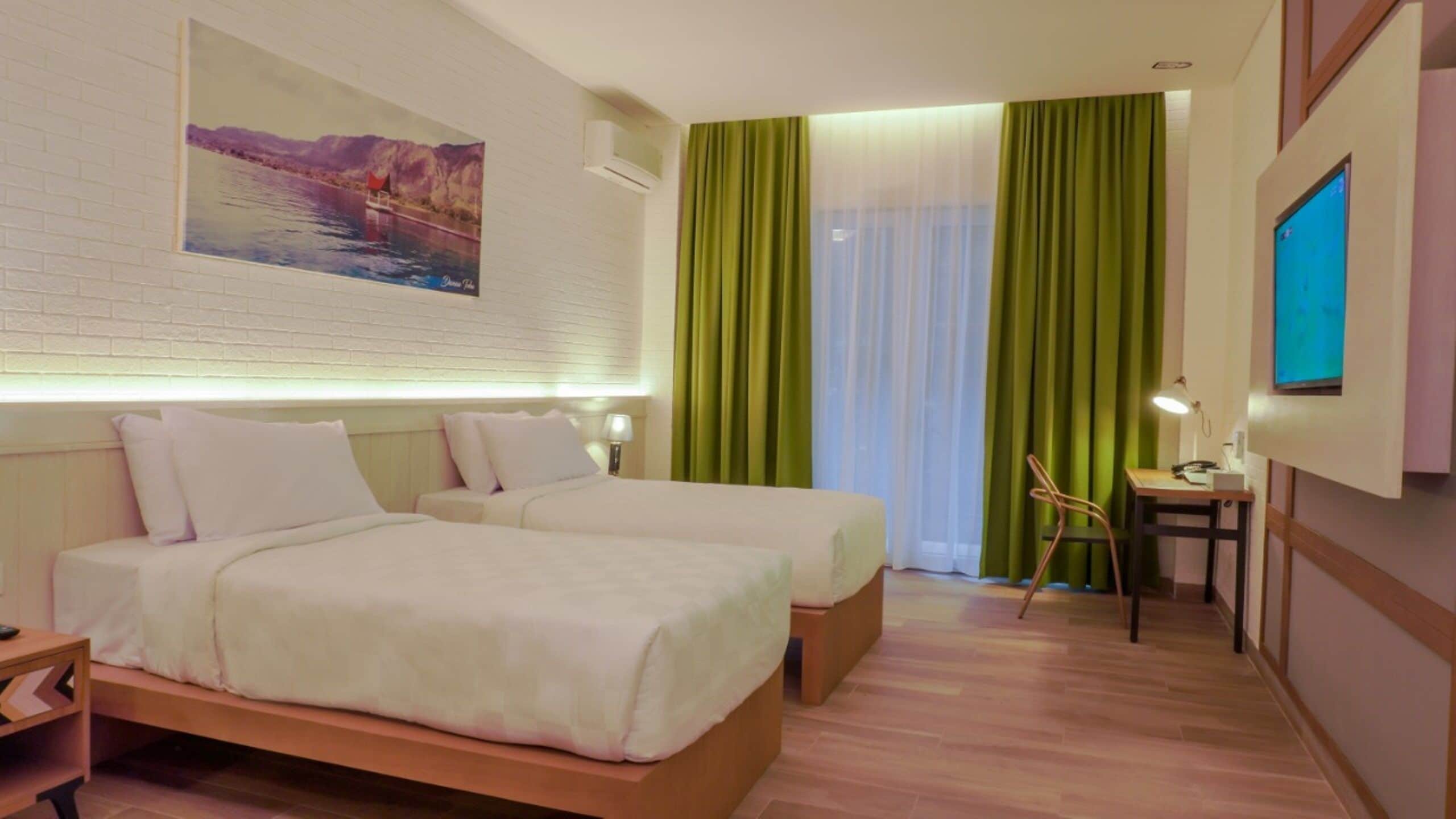 A hotel room with two beds, a desk, a chair, a TV, and a painting on the wall.