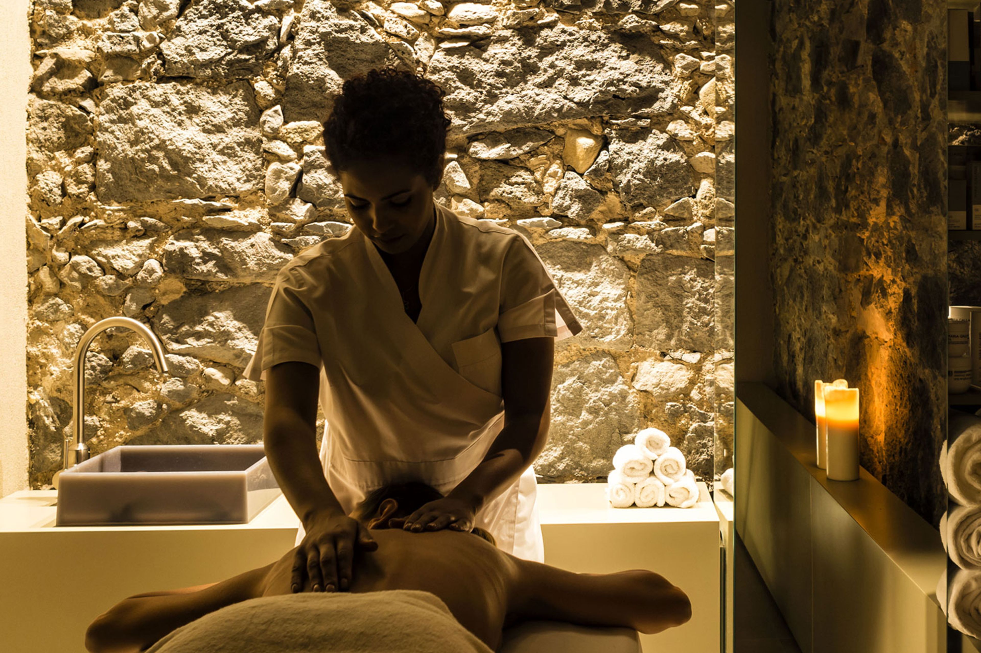 A spa setting with a stone wall, a sink, and towels.