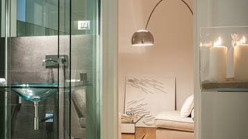 Un bagno moderno con cabina doccia in vetro, lavabo in vetro e lampada a sospensione dal design contemporaneo.
