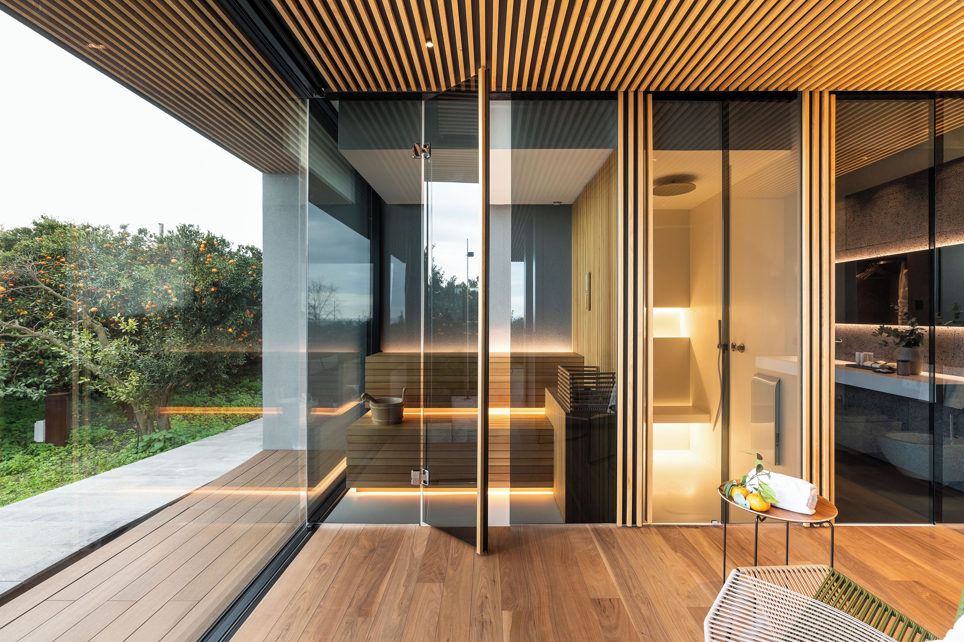 A modern interior with a glass door leading to a balcony, a wooden floor, and a small table with a towel and fruit.