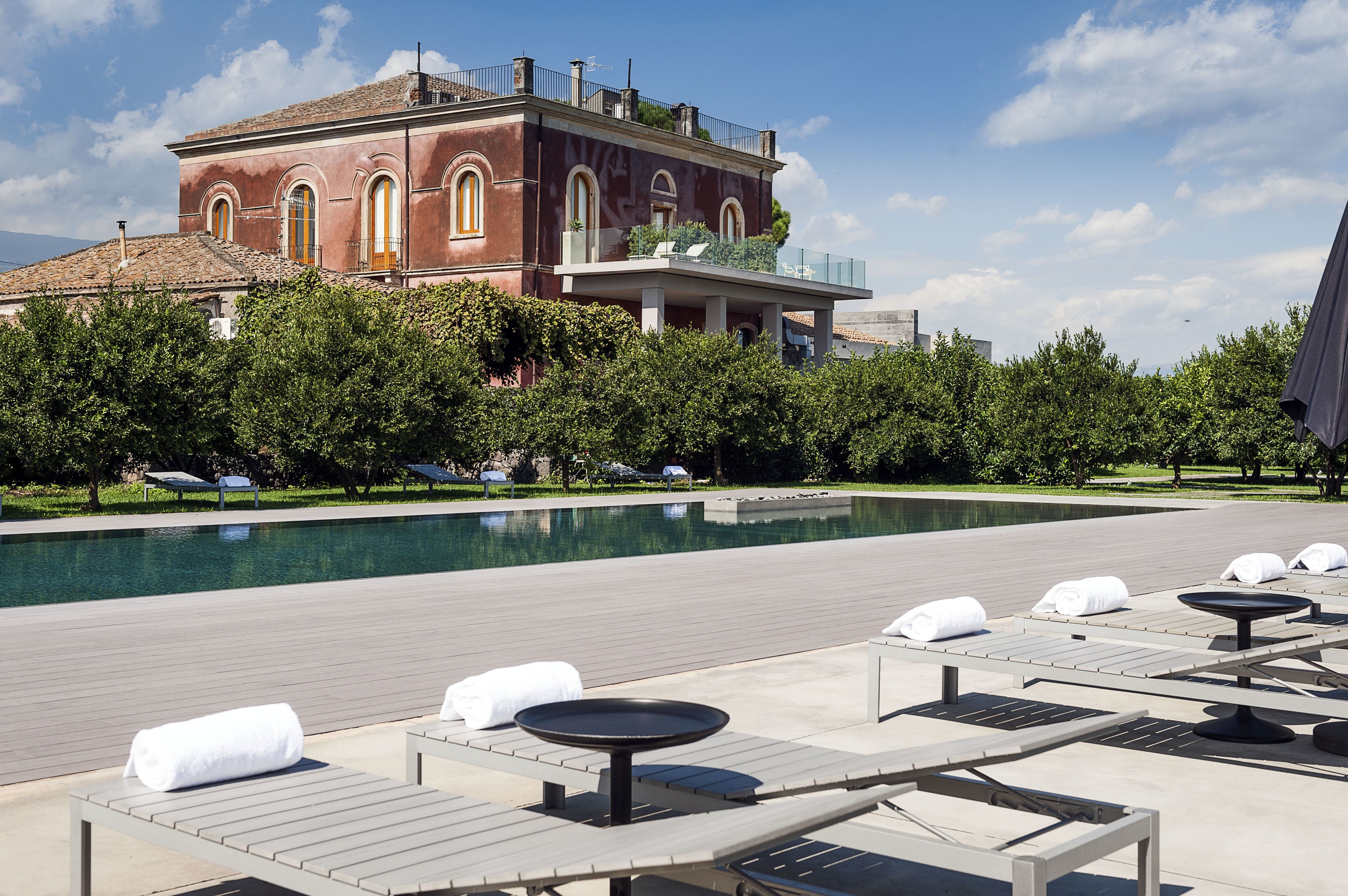 A poolside area with lounge chairs and a large building in the background.