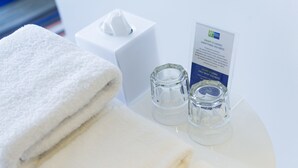 Une salle de bain bien rangée, avec une serviette blanche, une boîte de mouchoirs et un récipient en verre.