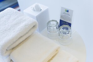A neatly arranged bathroom with a white towel, a tissue box, and a glass container.