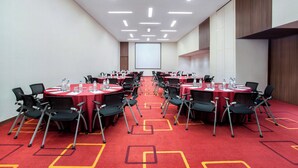 A conference room with multiple tables, chairs, and a projector screen. - Holiday Inn Express Jakarta Pluit Citygate by IHG (Jakarta)