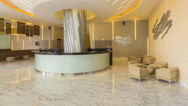 A modern lobby with a reception desk, seating area, and a large decorative column. - Holiday Inn Express Jakarta Pluit Citygate by IHG (Jakarta)