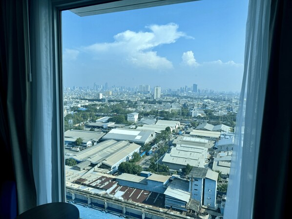 A view from a window overlooking a cityscape with industrial buildings and a distant skyline.