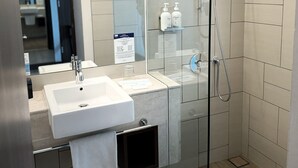 Une salle de bain moderne avec une douche à parois de verre, un lavabo blanc et un miroir.