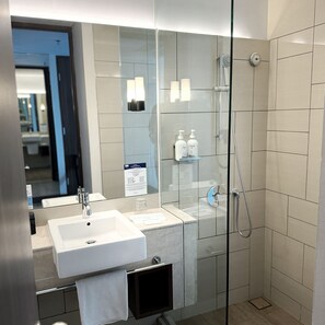 A modern bathroom with a glass-enclosed shower, a white sink, and a mirror.