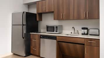 A kitchen with a refrigerator, microwave, dishwasher, and wooden cabinets.