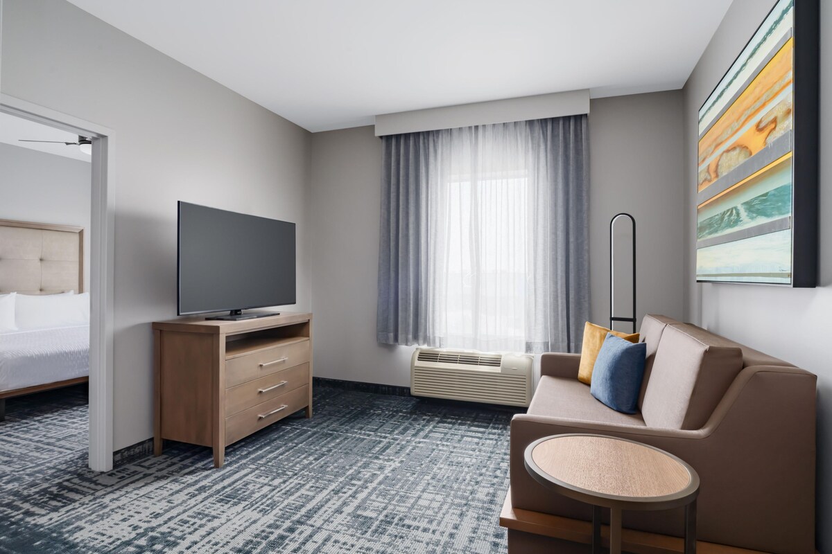 A hotel room with a bed, TV, sofa, and a small table.