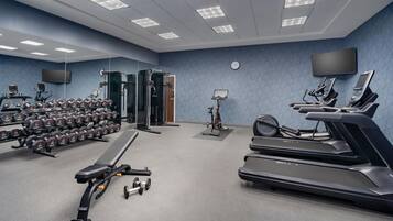 A gym with treadmills, dumbbells, and exercise equipment.