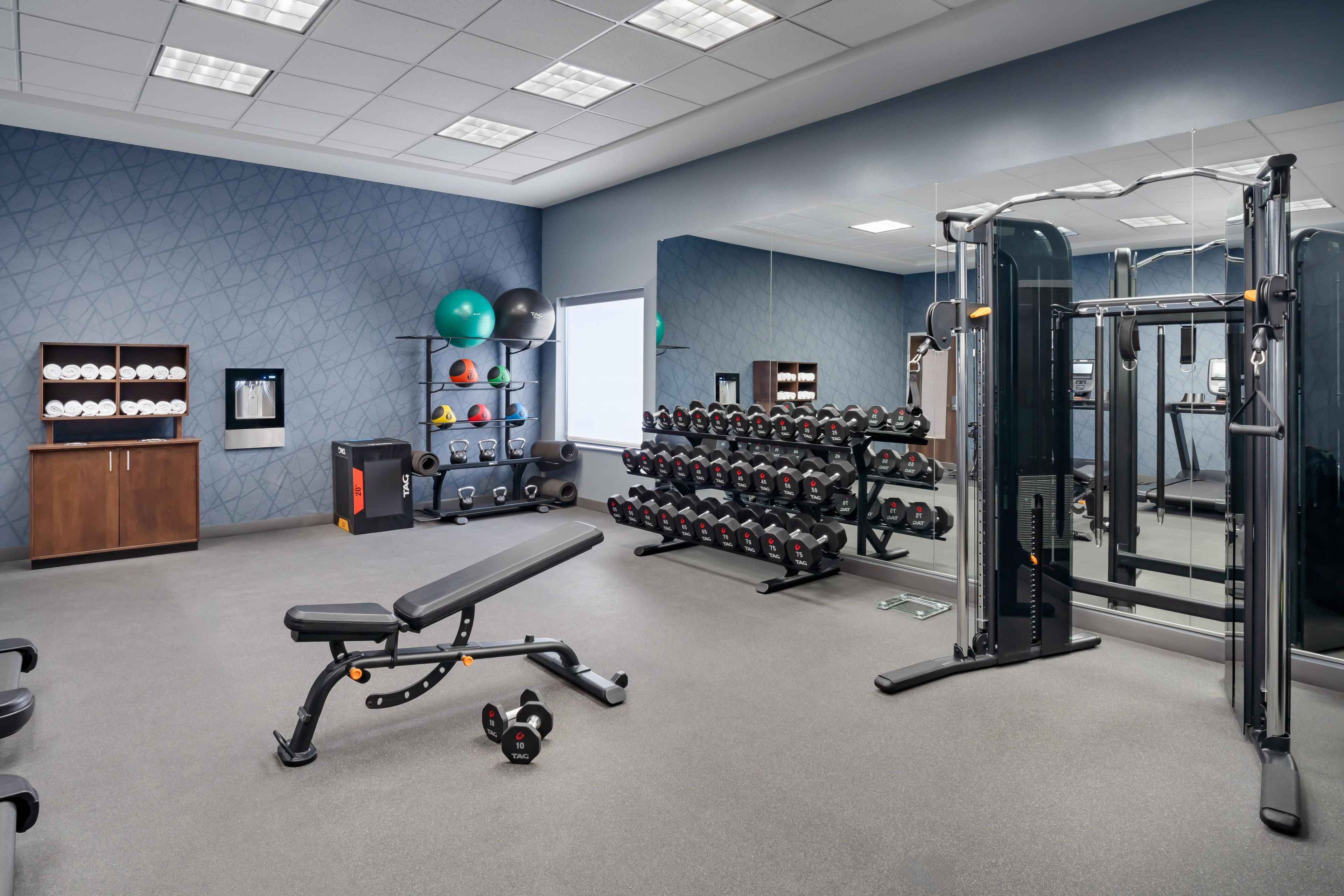 A gym with exercise equipment, a bench, and a wall-mounted mirror.