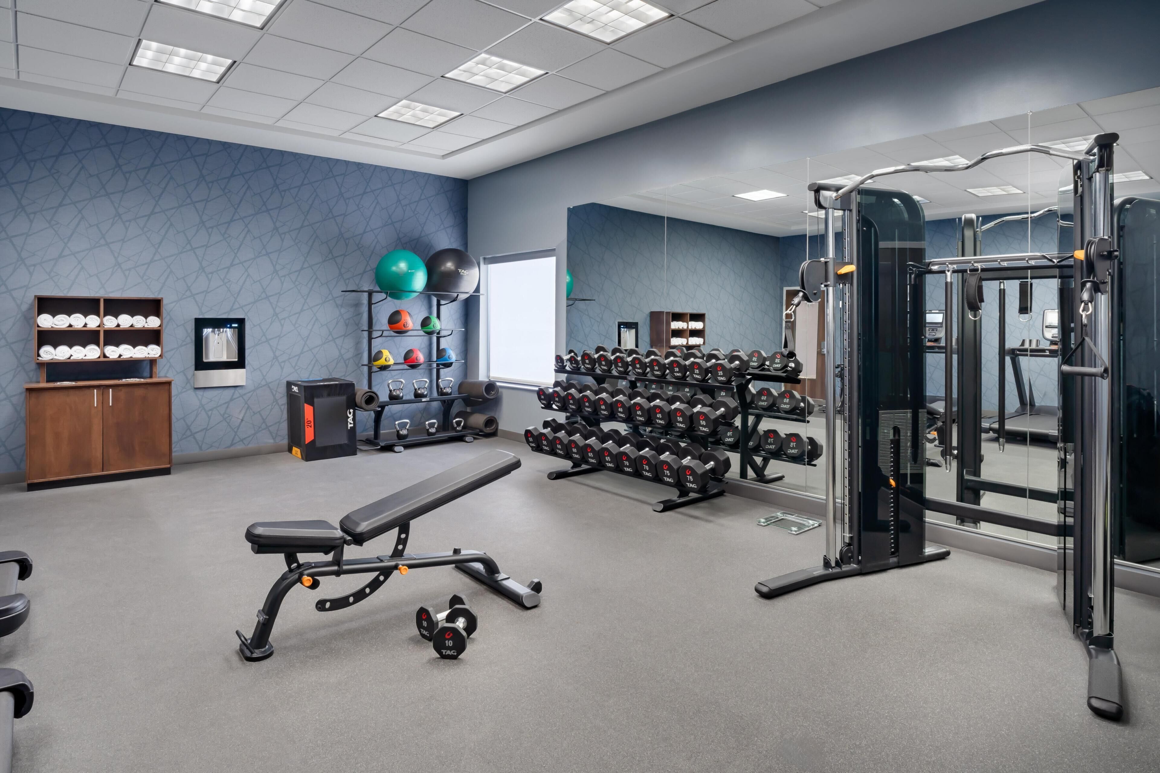 A gym with exercise equipment, a bench, and a wall-mounted mirror.