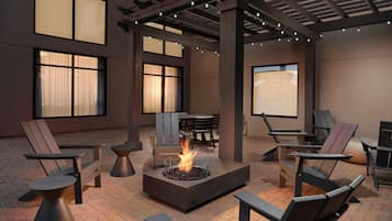 A patio area with outdoor seating, a fire pit, and large windows.
