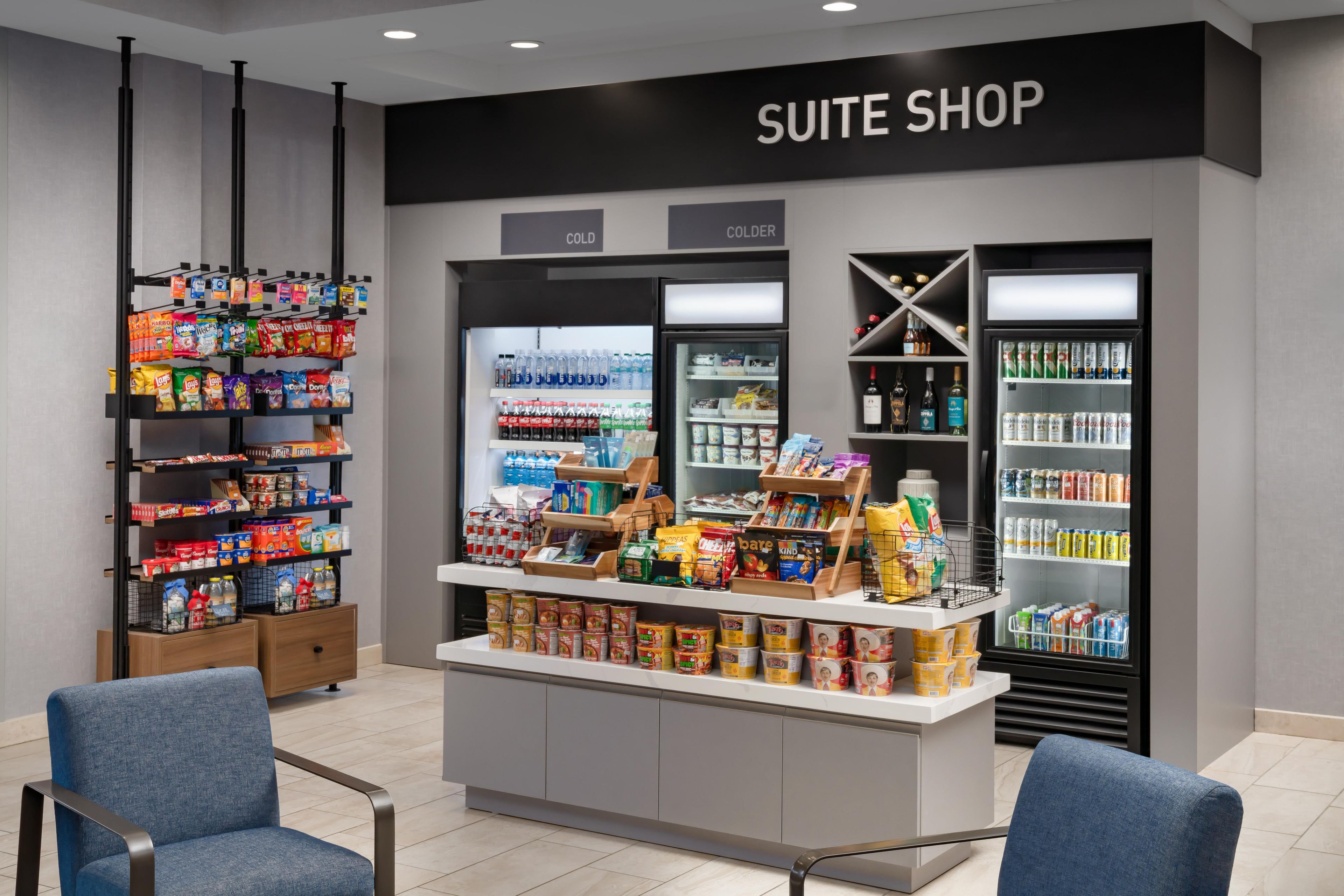 A suite shop with a refrigerated section, snack shelves, and a display of beverages.