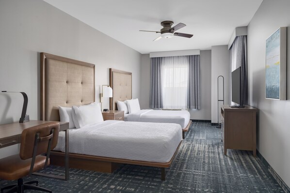 A hotel room with two beds, a desk, a chair, a ceiling fan, a TV, and a large window with curtains. - Homewood Suites by Hilton Midland, TX (Midland)