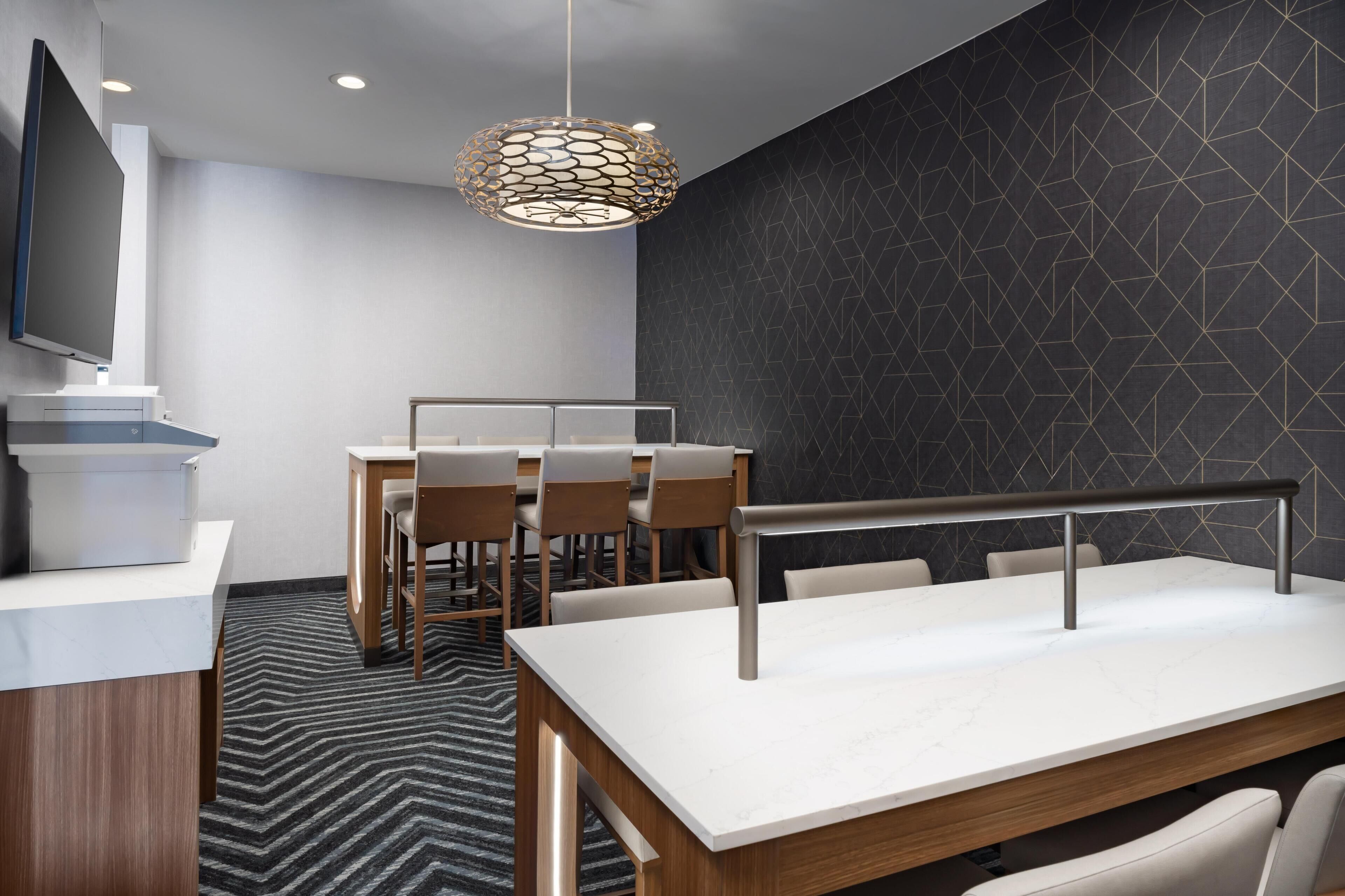 A modern conference room with a round table, chairs, a TV, and a unique patterned wall.