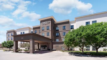 Un hotel de diseño moderno, una entrada cubierta y un letrero que indica que es un Homewood Suites by Hilton.