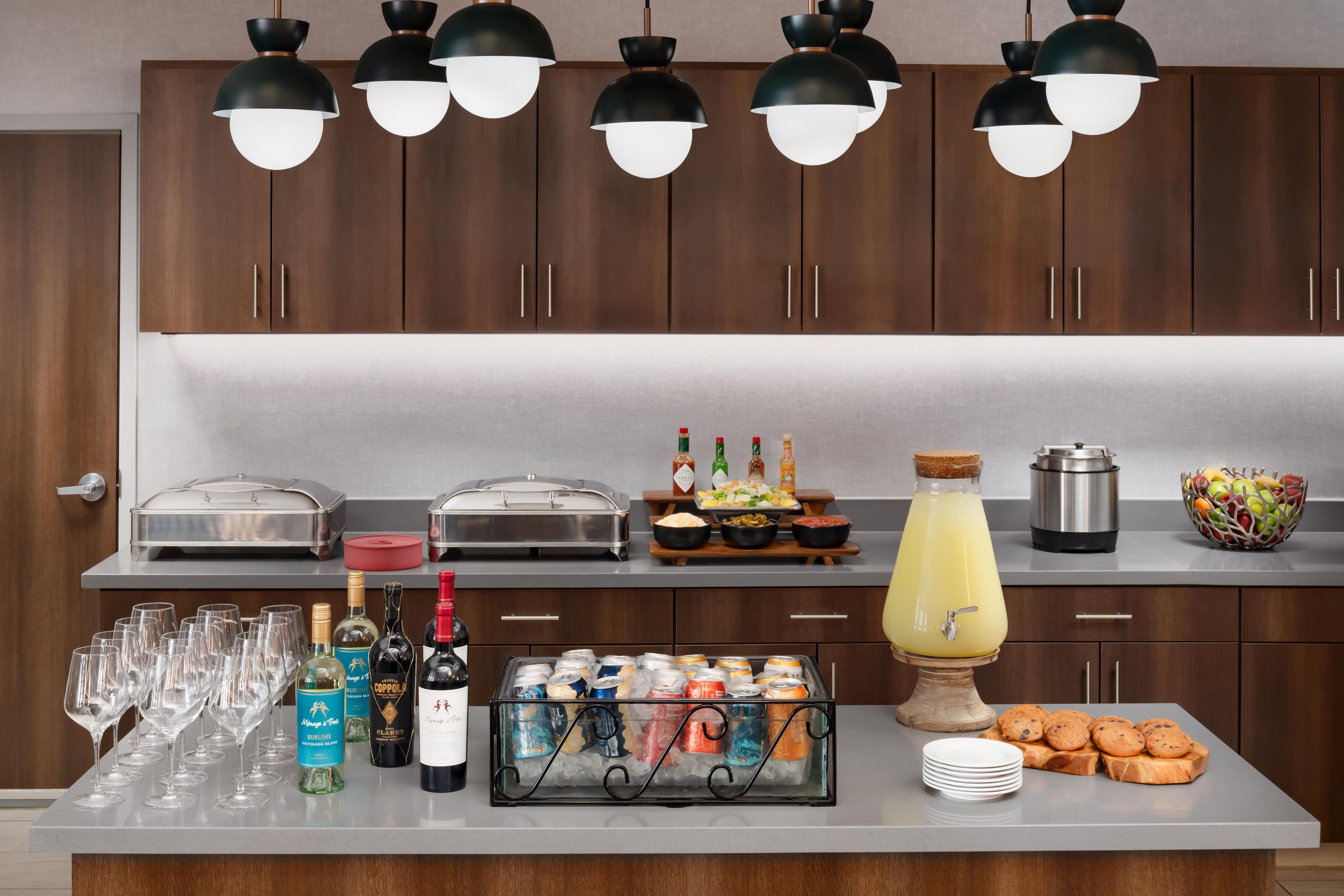 A buffet setup with various food items, beverages, and a fruit bowl.