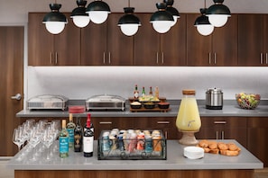 A buffet setup with various food items, beverages, and a fruit bowl. - Homewood Suites by Hilton Midland, TX (Midland)