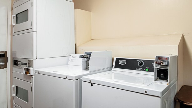 Une buanderie équipée de machines à laver et de séchoirs superposés, dont un modèle Maytag et un modèle Whirlpool.