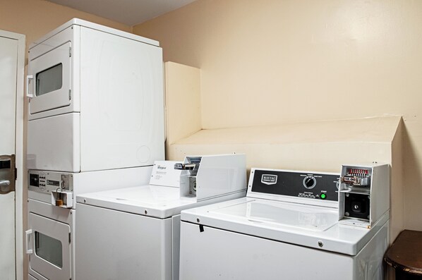 A laundry room with stacked washers and dryers, a Maytag dryer, and a Whirlpool dryer.
