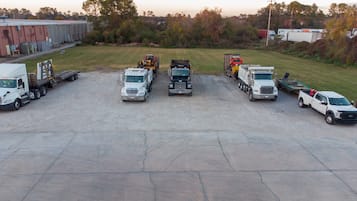 Un estacionamiento con varios camiones y un edificio al fondo.