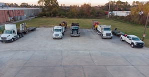 A parking lot with several trucks and a building in the background. - Red Roof Inn Slidell  (Slidell)