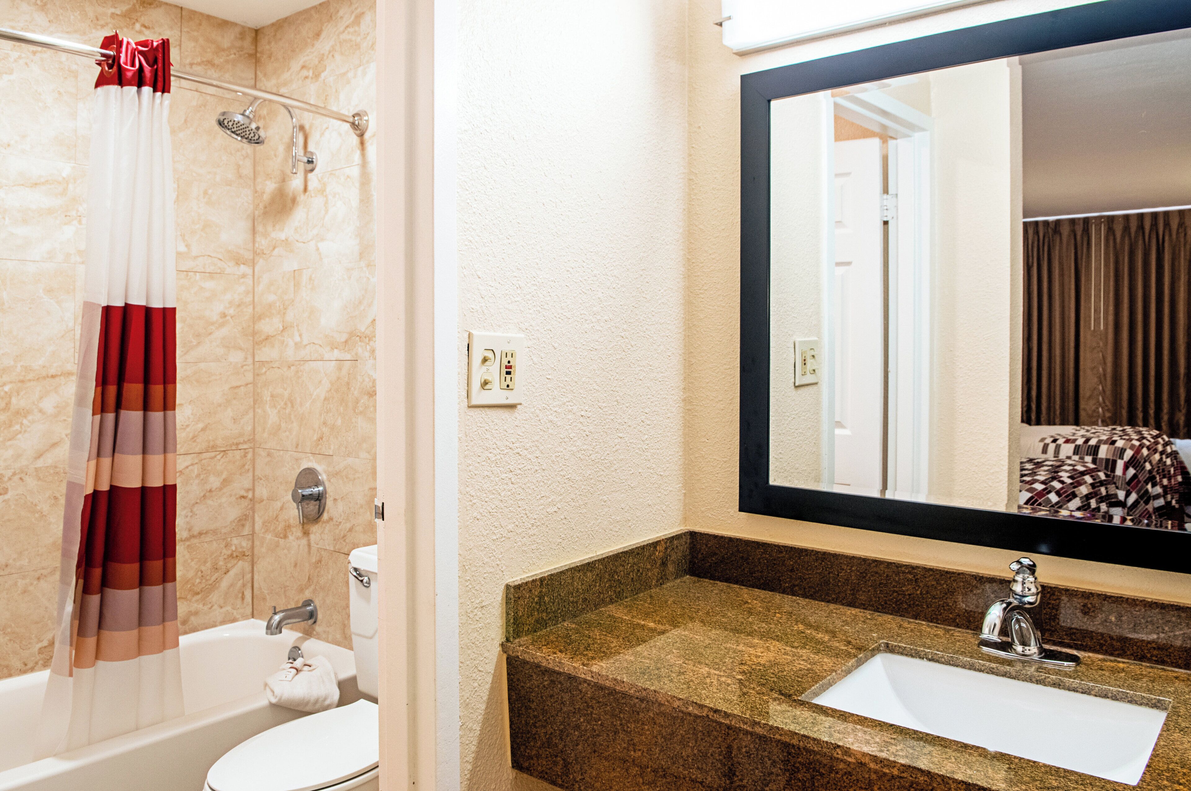Ein Badezimmer mit einer Badewanne, Toilette und einem Waschbecken mit Granitplatte.