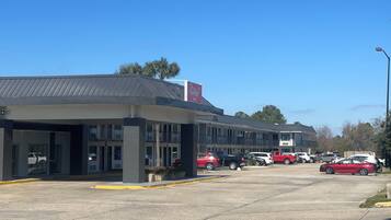A commercial building with a covered parking area and multiple vehicles parked.