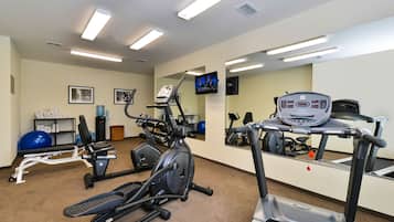 A gym with exercise equipment, a treadmill, and a mirrored wall.