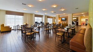A spacious hotel lobby with multiple seating areas, including sofas and tables, and a television mounted on the wall. - Sleep Inn & Suites Gulfport (Gulfport)