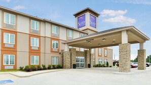 A multi-story hotel with a central entrance, stone pillars, and a sign for Sleep Inn Suites. - Sleep Inn & Suites Gulfport (Gulfport)