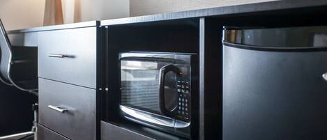 Una cucina moderna con forno a microonde integrato, frigorifero e un pensile con cassetti.