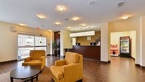 A lobby with two yellow armchairs, a reception desk, a vending machine, and a large window. - Sleep Inn & Suites Gulfport (Gulfport)