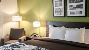 Une chambre d’hôtel avec un lit, deux lampes de chevet, une chaise et une table de chevet avec un téléphone.