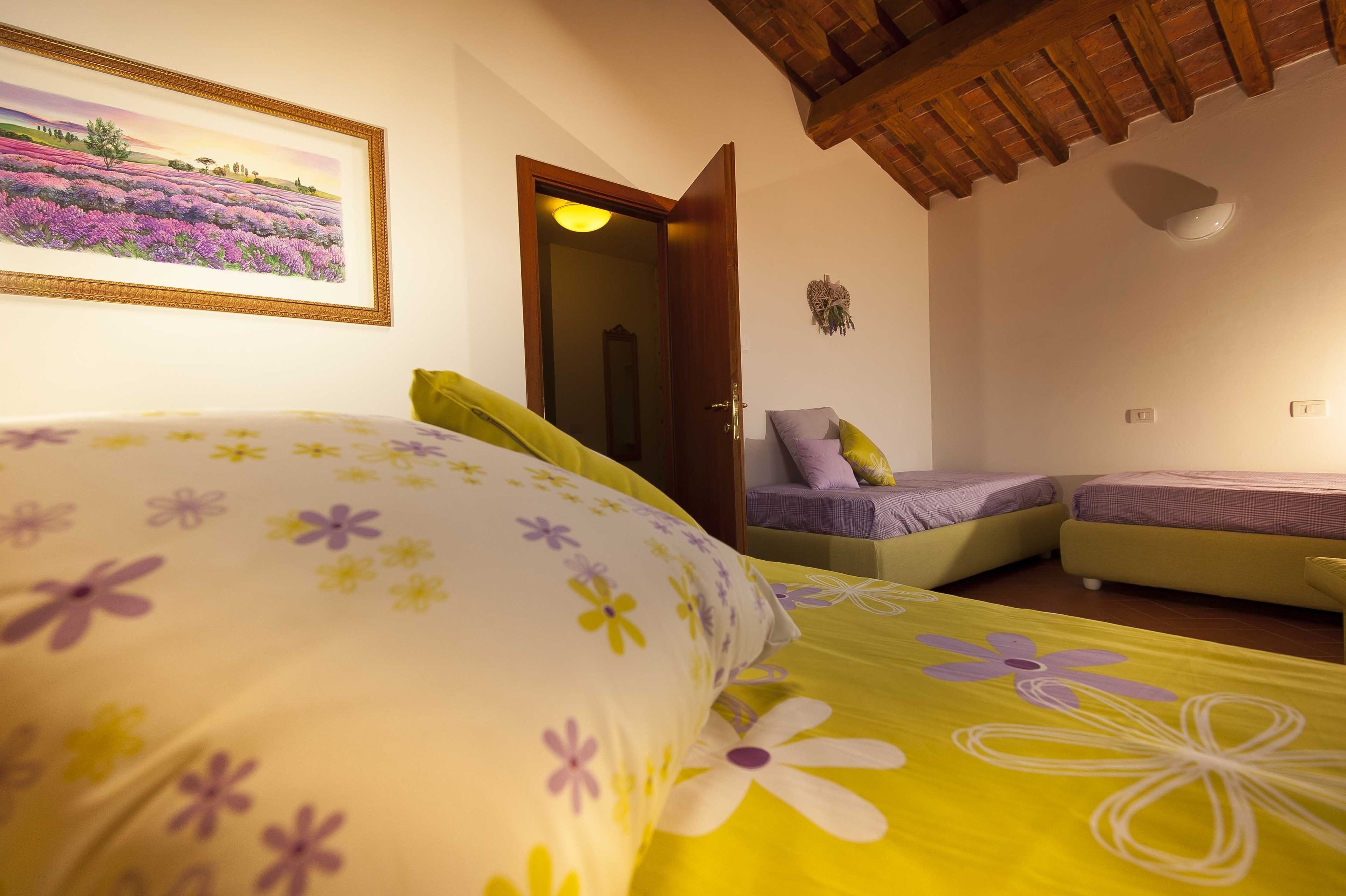 Un dormitorio con cama, dos mesitas de noche, una puerta y un cuadro en la pared.