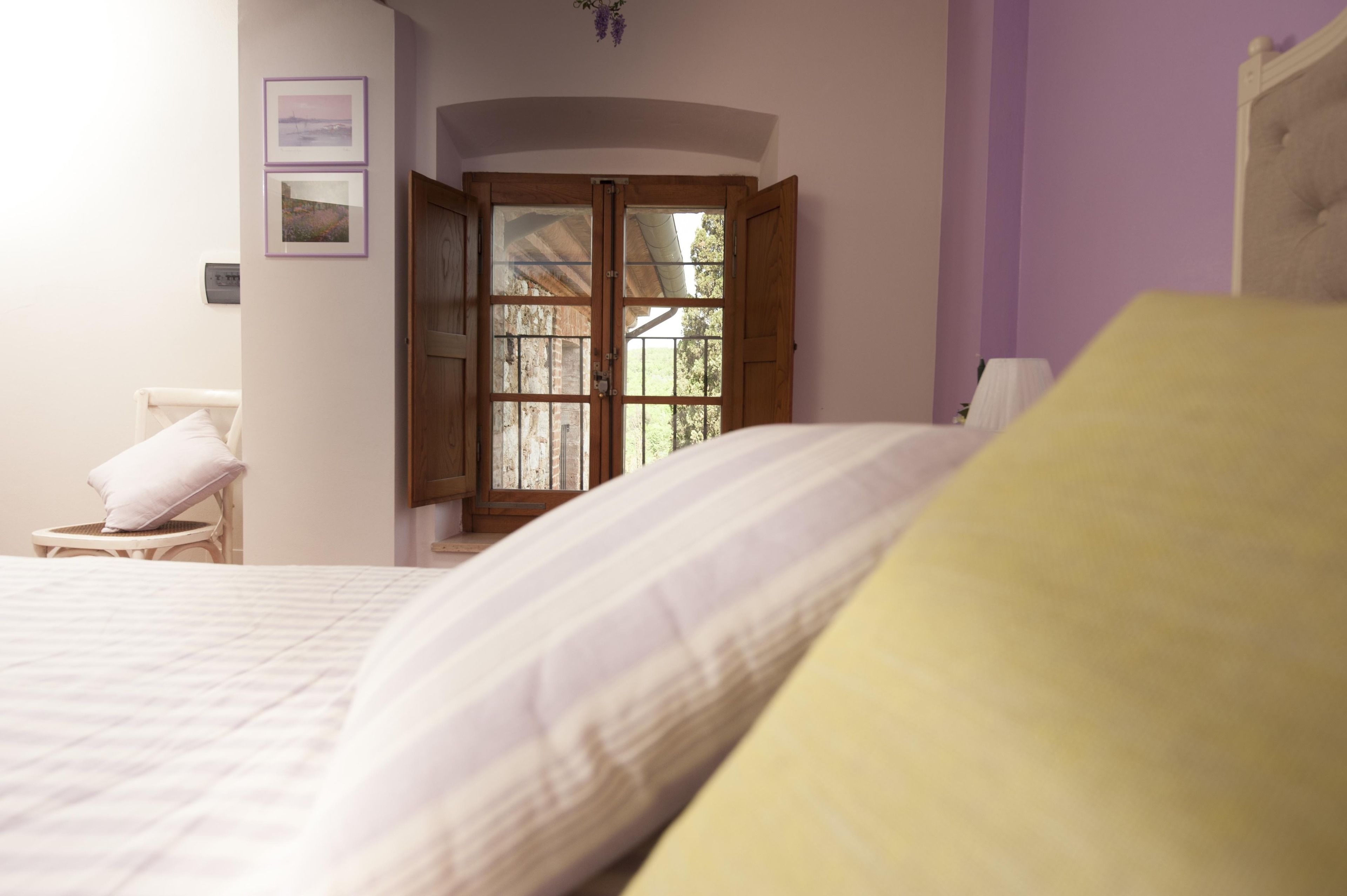 Ein Schlafzimmer mit Bett, Sessel, einer Holztür mit Glasfeldern und Blick ins Freie.