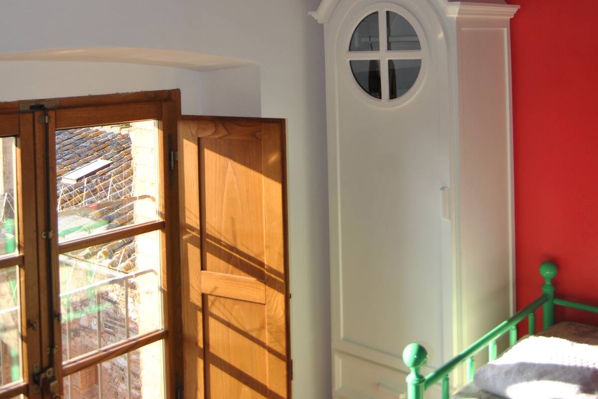 A room with a wooden door, a white armoire, and a red wall.