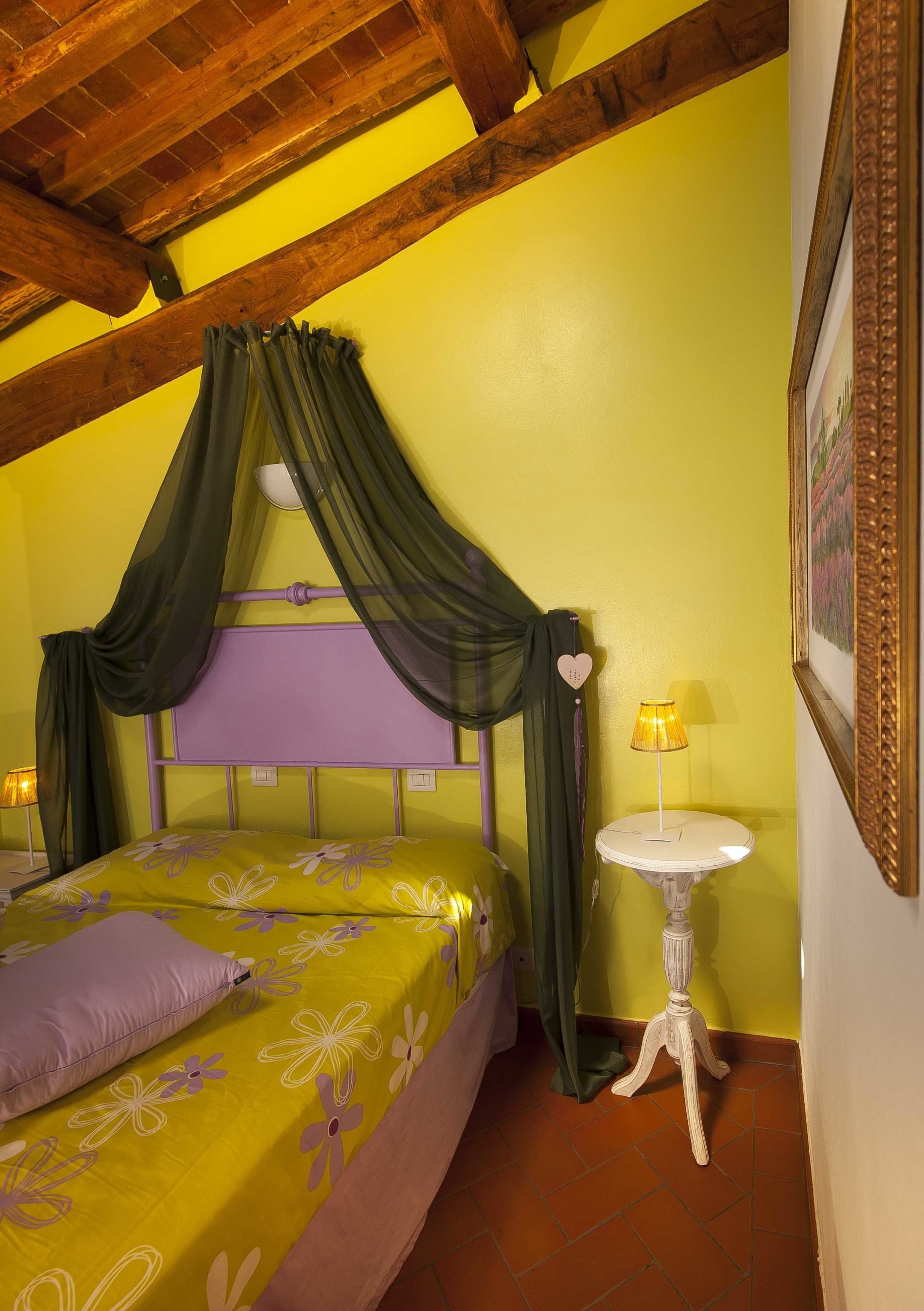 Une chambre à coucher avec un lit, une table de chevet, une lampe et un cadre photo fixé au mur.
