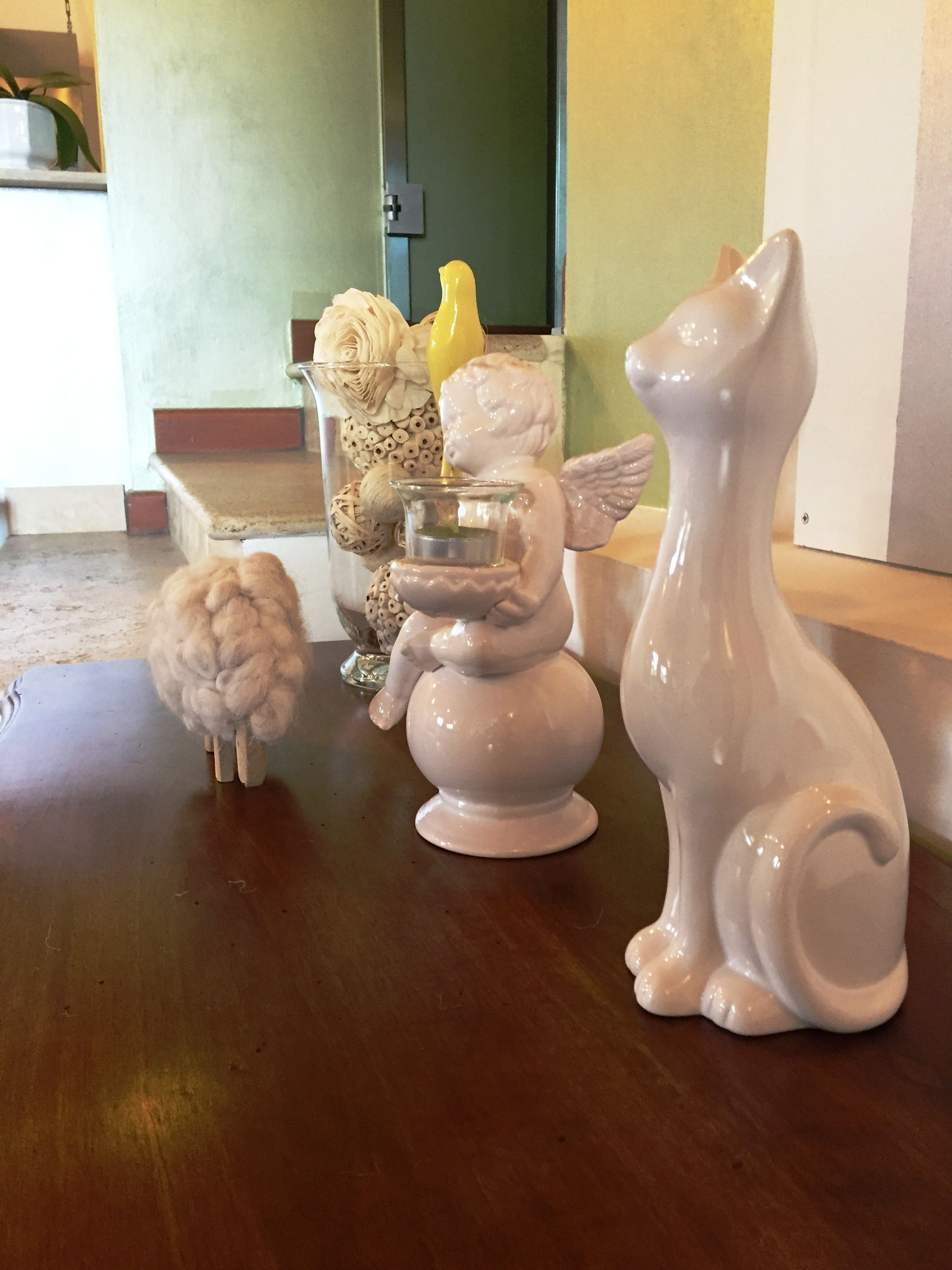 Uma mesa decorada com pequenas figuras de cerâmica, incluindo uma ovelha, um pássaro e um cão.