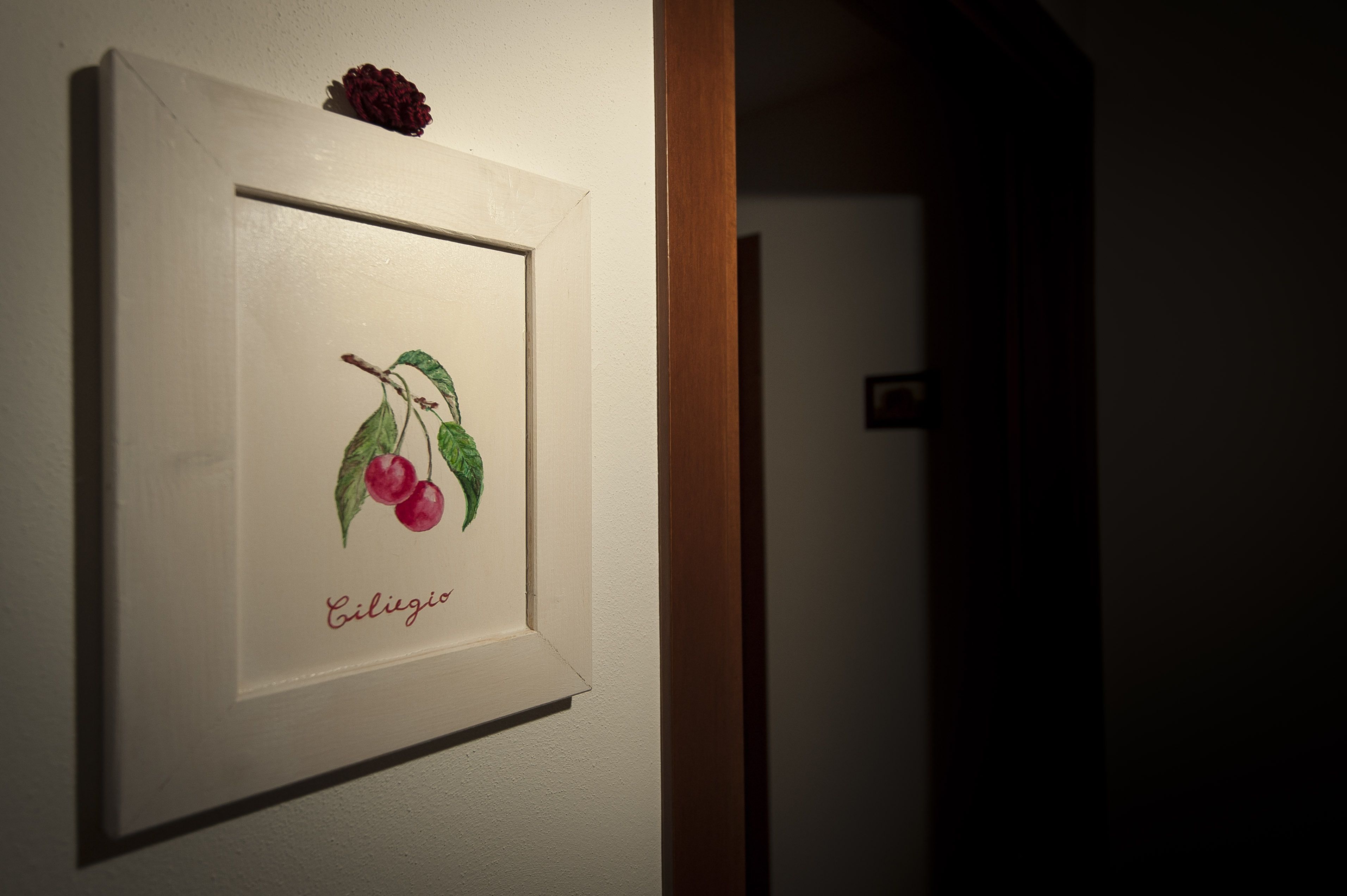 Ein gerahmtes Bild mit Kirschen an der Wand.