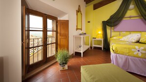 Un dormitorio con cama, mesita de noche, planta en maceta y ventana con vistas.